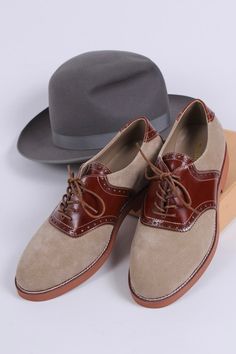 Casual men's two-tone 1950s-style oxford/saddle shoes with brogue pattern. These two-tone, 1950s-inspired, casual everyday oxfords feature an almond-shaped toe cap. The shoe is made of suede and features cognac brown full-grain leather with a brogue pattern on the backstay and around the vamp. The outsole is crafted from brown lightweight rubber with white stitching on the welt. These shoes have a casual, sporty, and authentic 50s look, pairing exceptionally well with jeans or wide trousers. The Beige Wingtip Oxfords For Formal Occasions, Retro Wingtip Oxfords With Brogue Detailing, Beige Brogue Oxfords For Formal Occasions, Formal Beige Brogue Oxfords, Retro Leather Wingtip Oxfords, Brown Dress Shoes With Rubber Heel Cap For Derby, Classic Beige Almond Toe Oxfords, Retro Wingtip Oxfords For Business, Retro Wingtip Oxfords Shoes