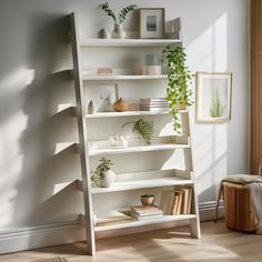 a white book shelf filled with books and plants