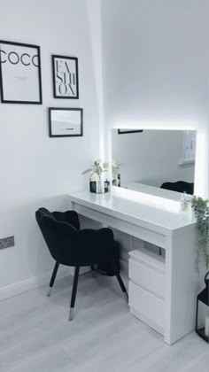 a white desk with a mirror, chair and vase on it in a room that is decorated with black and white pictures