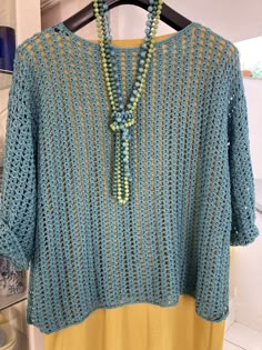 a blue crocheted sweater with beads hanging from it