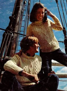 two people are sitting on the deck of a ship and one person is taking a photo