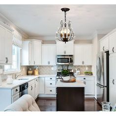 a kitchen with white cabinets and an island in front of the stove, refrigerator and microwave