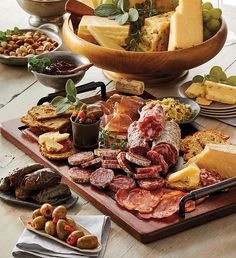 an assortment of meats and cheeses on a wooden platter