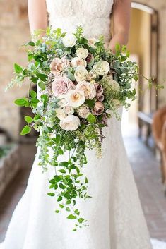 a bride holding a bouquet of flowers and greenery