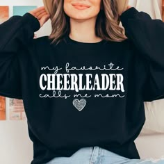 a woman wearing a black sweatshirt that says, my favorite cheerleader calls me mom