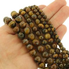 a hand holding several brown beads in it's palm, on a white background