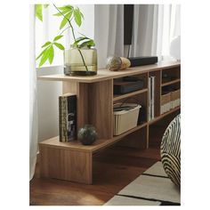 a wooden shelf with some books on top of it and a plant in the corner