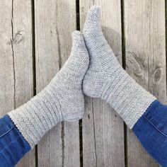 two pairs of feet with socks on top of wooden planks in front of them