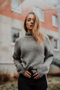 a woman standing in front of a building with her hands on her hips and looking off to the side