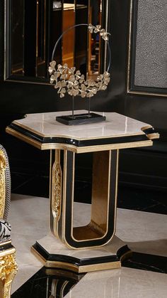 a gold and black table with a mirror in the corner next to an ornate chair