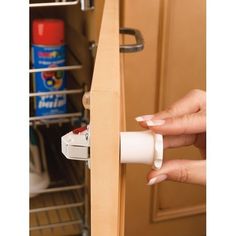 a woman is opening the door to her kitchen cabinet with an empty roll of toilet paper