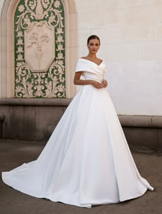 a woman in a white wedding dress posing for the camera with her hands on her hips