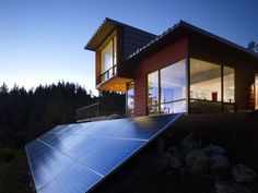 a house with a solar panel on the roof and some trees in the back ground