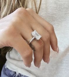 a close up of a person wearing a ring with a baguette on it