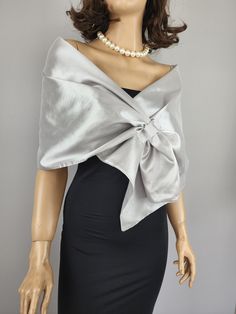 a mannequin wearing a dress with a bow at the back and pearls around the neck