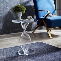 a glass table with a vase on it and a blue chair in the back ground