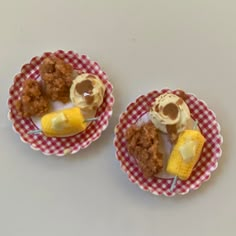 two miniature plates with food on them sitting on a table