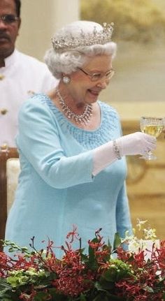 the queen of england is holding a glass of wine