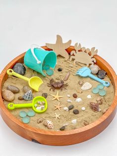 a wooden bowl filled with sand and toys