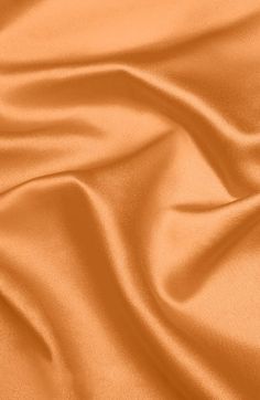 an orange silk background with very soft folds and smooth lines on the fabric in this image