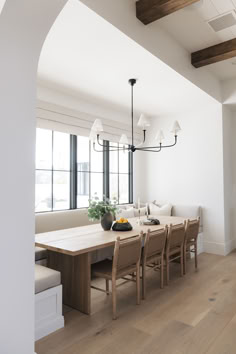 a dining room table with chairs and a bench in front of a large window on the wall