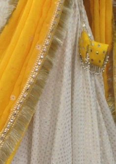 Haldi yellow lehenga with mirror work. The blouse is made of rawsilk with flutter sleeves in chiffon and all over mirror work. Skirt is made of brocade and has wide mirror work borders. Chiffon dupatta with sequins and mirror work. The dress will be made to order in your size. I'll send you a measurement sheet once you order for the measurements. Dress can be created in any color as the fabric is custom dyed. Please convo me if you have any questions or need any customisation. White And Yellow Lehenga For Haldi, White Sharara With Cutdana For Diwali, White Cutdana Sharara For Navratri, White Sharara With Cutdana For Navratri, Festive White Cutdana Sharara, Eid Anarkali Pre-draped Saree With Gota Work, White Sharara With Cutdana In Traditional Drape, White Kundan Lehenga With Cutdana, White Chanderi Sharara With Traditional Drape