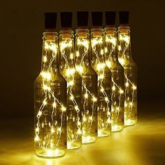 six bottles with lights in them sitting on a table next to each other and one is empty