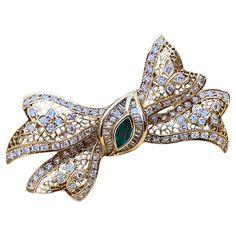 Diamond and Emerald Bow Pin Brooch with Filigree in 18k Yellow Gold Emerald and Diamond Bow Pin features Round Brilliant cut Diamonds and Baguette Diamonds weighing a total of 2.89 carats with one Marquise Green Emerald in the center weighing 0.41 carat, all set in 18k Yellow Gold. The pin is secured by a single bar clasp with safety and has 2 bales on the back side for wearing as a pendant. Total diamond weight is 2.89 carats. Total emerald weight is 0.41 carat. Pin measures 2.05 inches across and 1.25 inches down. The pin weighs 15.7 grams. Made of 18k Yellow Gold. Marked 18k, 0.41, D2.89 BUY WITH CONFIDENCE Authenticity is guaranteed for every item we sell. Yellow Gold Diamond Brooches Fine Jewelry, Luxury Yellow Gold Diamond Brooches, Luxury Yellow Gold Brooches With Gemstones, Luxury Green Diamond Brooch, Luxury Green Pendant-shaped Brooches, Diamond Bows, Emerald Stone, Gold Filigree, Bezel Diamond