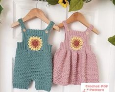 two crocheted baby rompers hanging on a door with flowers in the background