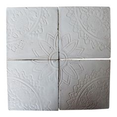 four white tiles with intricate designs on the sides and one has a cross in the middle