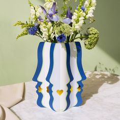 a blue and white striped vase with flowers in it on top of a marble table