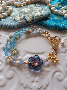 Delightful selection of Springtime soft blue & white tones in in this Bohemian Beaded bracelet. This bracelet has been made with love and I have used assorted selection of super cute Czech glass beads, including these super cute Czech Pansy flowers, some pearls, Aqua blue Agate Rondelles and the most gorgeous Blue Frangipani focal bead. To add to the theme of Springtime I have added a super cute Gold Vermeil Bee charm as well. I have also used pretty gold  CZ clasp and included a extender chain Blue Bohemian Crystal Bracelet With Round Beads, Handmade Vintage Blue Beaded Bracelets, Bohemian Light Blue Flower Jewelry, Elegant Handmade Light Blue Beaded Bracelets, Light Blue Beaded Flower Jewelry, Blue Flower Shaped Beaded Bracelet For Gift, Light Blue Flower-shaped Beaded Jewelry, Handmade Light Blue Beaded Bracelets, Blue Bohemian Flower Bracelets