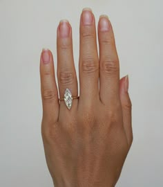 a woman's hand with a diamond ring on her left hand, against a white background