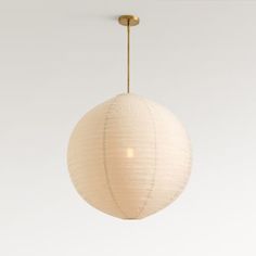 a white paper ball hanging from a brass colored ceiling fixture with a light bulb on the end