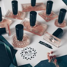 several different types of nail polish sitting on top of a piece of paper next to some flowers