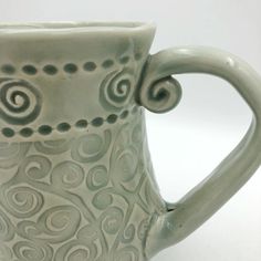 a white ceramic cup with swirl designs on it