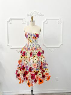 a dress made out of flowers on a mannequin head stand in front of a white wall