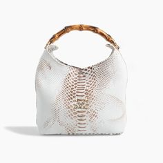 This white leather handbag elegantly combines a sleek, embossed design with a distinctive bone handle in a bamboo-like appearance, highlighted by gold metallic details.  Meticulously handcrafted from genuine leather and lined with durable gabardine fabric, it features a magnetic closure for security.  The bag's refined bone handle, adorned with gold accents, elevates its aesthetic, while an interior zip pocket and an adjustable leather strap offer versatility, making it suitable for shoulder or Gabardine Fabric, Embossed Design, Top Handle Bags, Leather Handbag, Magnetic Closure, Gold Accents, White Leather, Purses And Handbags, Leather Handbags