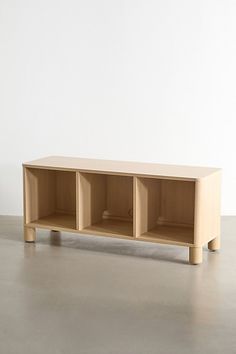 a wooden shelf sitting on top of a floor next to a white wall with three shelves