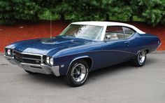 a blue and white muscle car parked in a parking lot