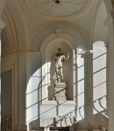 a statue in the middle of a room with sun coming through it's windows