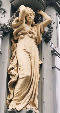 a statue on the side of a building with a woman holding her head in her hands