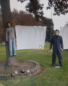 two boys are playing frisbee in the park with one boy standing next to a tree