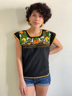 "Vibrant floral embroidered black Mexican top, ethnic boho hippie top, EXTRA SMALL Mexico blouse women, yellow orange white flowers, Puebla This Vibrant floral embroidered black Mexican top is an exceptional piece of clothing that showcases the beauty of traditional Mexican embroidery. The top features an exquisite multicolor floral embroidery in hues of yellow, orange, and white that creates a stunning contrast against the black base. The flowers are intricately sewn, giving the top an eye-catc Orange White Flowers, Mexican Top, Bandana Bow, Hippie Top, Mexican Embroidery, Mexican Blouse, Mexican Outfit, Hand Embroidered Flowers, Hippie Tops