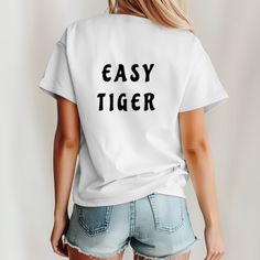 Easy Tiger T-Shirt, Graphic T-Shirt, Animal Gift Idea, Tiger Graphic T-Shirt, Vintage Inspired Shirt, Trendy Tiger T-Shirt , Boho Clothes Unleash your inner cool with our "Easy Tiger"  unisex t-shirt. Perfect for those who blend laid-back vibes with a hint of wild spirit, this tee is a stylish and comfortable addition to any wardrobe. Whether you're out on an adventure or just chilling at home, this shirt will keep you feeling and looking effortlessly cool. Hand-crafted designs by WildDayDreamer Trendy T-shirt With Funny Text For Everyday, Trendy Everyday T-shirt With Funny Text, Trendy Everyday Shirt With Letter Print, Trendy Funny Text T-shirt For Everyday, Trendy Tops With Funny Text For Everyday, Casual Tops With Funny Text For Everyday, Casual White T-shirt With Funny Text, Casual Everyday Tops With Funny Text, Basic T-shirt With Letter Print