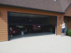 a woman standing in front of a garage with her bike and two cars parked inside