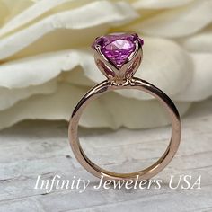 "This ring is a round cut lab created pink sapphire solitaire in 14k rose gold #6465 -Approximate total carat weight: 2.70ctw. diamond equivalent -Center Stone Size: approx. 2.70ct diamond equivalent -Center Stone Shape: round cut / 9 MM -Gem Type: lab created pink sapphire -Stone Clarity: VS2 -Stone Color: Medium Pink -Moh's Scale: 9 hardness -Metal Type and Purity: 14k rose gold -Setting: classic Tulip 4 Prong Setting -Stock Ring Size: 6 -Country of Manufacturing: USA (Michigan) For customizat Pink Brilliant Cut Round Ruby Ring, Pink Brilliant Cut Ruby Ring, Pink Round Cut Ruby Ring, Pink Round Cut Ruby Ring In Fine Jewelry Style, Pink Brilliant Cut Ruby Ring For Gift, Fine Jewelry Pink Ruby Ring With Round Cut, Pink Brilliant Cut Ruby Ring Gift, Fine Jewelry Pink Round Cut Ruby Ring, Pink Sapphire Round Cut Ring