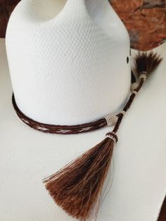 Braided Horse Hair Adjustable Hat Band with 2 Tassels with 2 sliding hitched knots that make this hatband a great fit for most hats. This stunning hat band is made from genuine braided horse hair and will compliment your favorite cowboy hat.   -  3 braided strands are sewn together to create this gorgeous hatband. - Incudes 2 horse hair tassels that measure 3 1/4" long - The tassels can be worn in the back or on the side. - Hat band measurements: approximately adjusts from  22 1/2" to 29" around and is 3/8 inch wide - Hat bands are shown on a size 7 hat.  Hats are not included. See my horse hair keepsakes to have a hat band made from your horse's hair:  https://www.etsy.com/shop/BlueEyesDesignsHB?ref=seller-platform-mcnav§ion_id=43697745 See my other hatbands:   https://www.etsy.com/shop/B Beach Hats With Adjustable Ties, Adjustable Brown Mini Hats Country Style, Traditional Mini Hats With Adjustable Short Brim, Traditional Adjustable Mini Hat With Short Brim, Traditional Adjustable Mini Hats With Short Brim, Western Hat Bands For Rodeo, Western Style Hat Bands For Rodeo, Adjustable White Hat Band For Country Events, Traditional Adjustable Hat With Short Brim