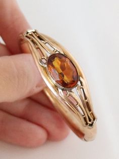 "Please note we ship on Tuesdays and Fridays only due to living in a Rural community. (THIS ITEM IS NOT GOLD PLATED IT IS ANTIQUE OR VINTAGE GOLD FILLED PLEASE READ EPLANATION FOR VINTAGE AND ANTIQUE GOLD FILLED JEWELLERY BELOW THE DESCRIPTION) This is an Edwardian Rose Gold Filled Topaz Glass Stone Bangle early 1900s and for a petite wrist only. Inside circumference is 14.5cms or approximate 5.75 inches. Good Antique condition. No dings or dents. Push button to open and snap shut. Hinge can gape occasionally but secures back in Stone is paste and is multi faceted and bezel set with open back to let the light shine through. Weighs 13.7gms. Band is 6-7mm wide. Stone is 1.6cms wide. Suitable for petite woman or discerning teenager. Signed on  the inside band A C Co (Attleboro Chain Company U Antique Citrine Gold Jewelry, Antique Gold Citrine Jewelry, Vintage Citrine Yellow Gold Jewelry, Heirloom Faceted Gold Jewelry, Vintage Yellow Gold Citrine Jewelry, Formal Hallmarked Citrine Jewelry, Heirloom Gemstone Bracelet Jewelry, Heirloom Gemstone Bracelet, Heirloom Gold Gemstone Bracelets