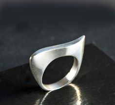 Elegant classic ring featuring a modernist wave design. The ring's fluid curves make an abstract art statement and it has a beautiful handmade look and feel. The ring's inner diameter is about 18.14, making the size a US size 8. The band measures 4 mm wide and is marked 925. The silver band has a few tiny nicks and scratches, consistent with wear and age. When wearing the ring, you don't notice these scratches - what you notice is the beauty of the ring's design and the excellent craftsmanship. Please zoom in each picture to see the tiny dings and scratches that are naturally acquired over time. These can be polished out, however, such marks are part of the ring's history and I'd recommend that you leave the marks and add your own personality and history to the piece :)  The pictures in my Modern Wavy Rings With Polished Finish, Modern Curved Rings With Polished Finish, Modern Curved Jewelry With Polished Finish, Modern Silver Wavy Rings, Modern Wavy Jewelry For Formal Occasions, Abstract Ring, Modern Silver Ring, Hollow Ring, Art Statement